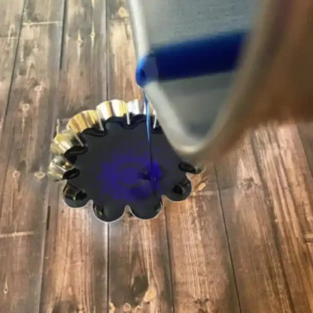 pouring wax into floating candle mold to the top of mold