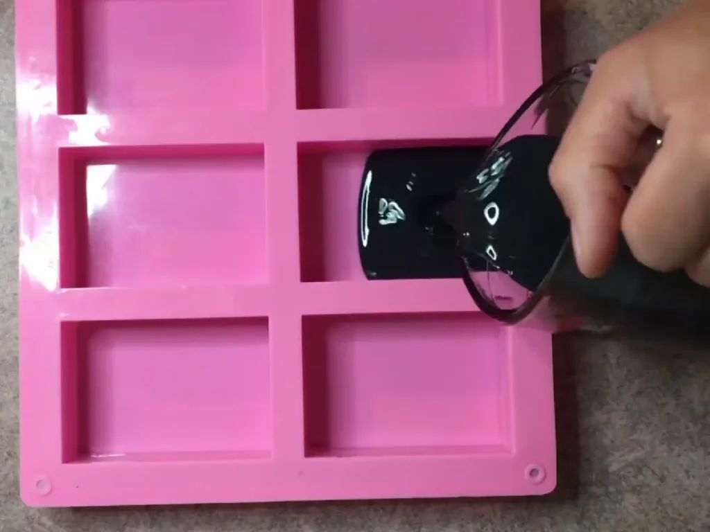 pouring activated charcoal into soap mold