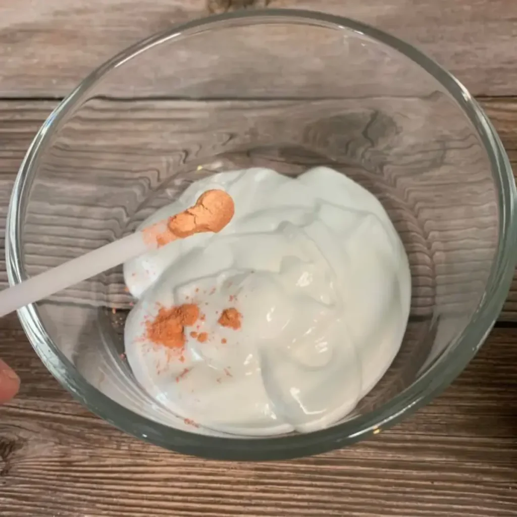 adding orange mica powder to whipped sugar scrub