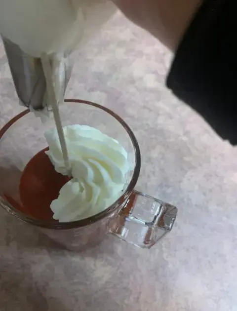 piping whipped wax frosting onto candle 