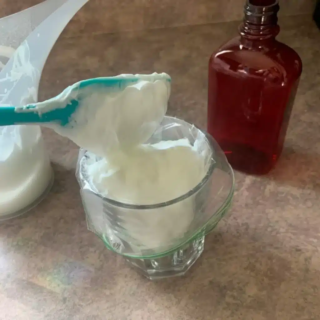 scooping thick lotion into a pipping bag