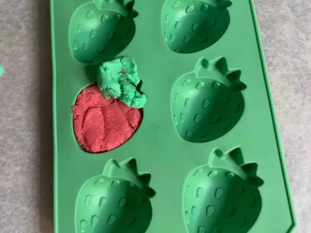 Placing the strawberries in mold adding green top