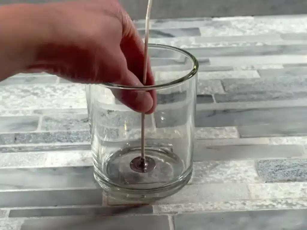 placing a candle wick into a jar