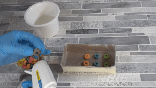 gluing fruit loops to box to make a mold