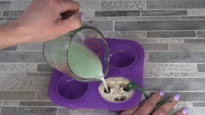 pouring melt and pour soap into mold over luffa sponge