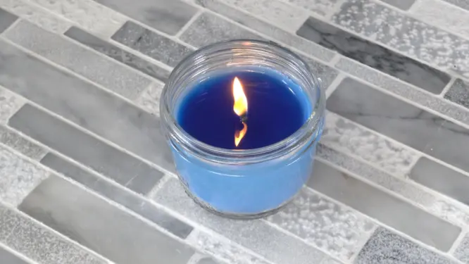 lit candle that is burned all the way to the edge of container