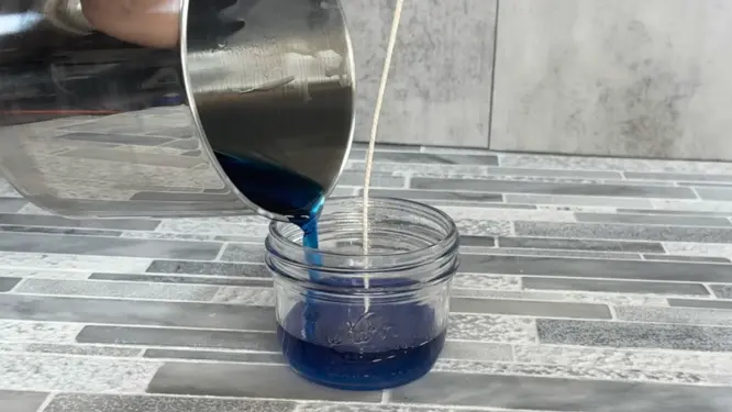 pouring homemade candle into jar