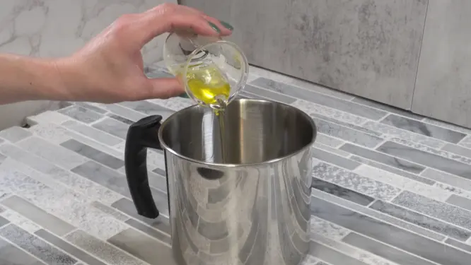 adding carrier oils to melted wax mixture for massage candle