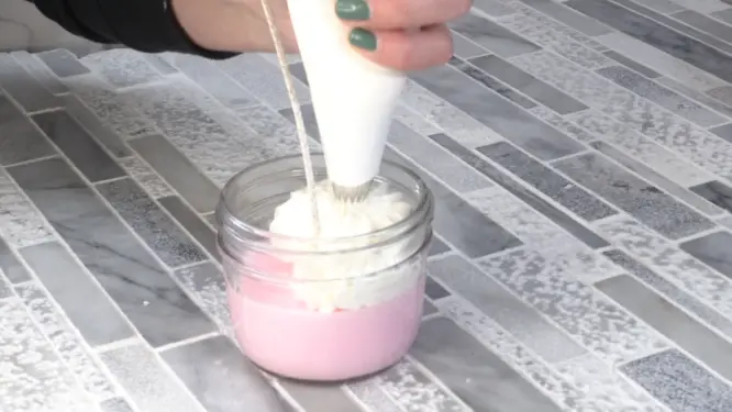 piping whipped candle wax onto candle surface
