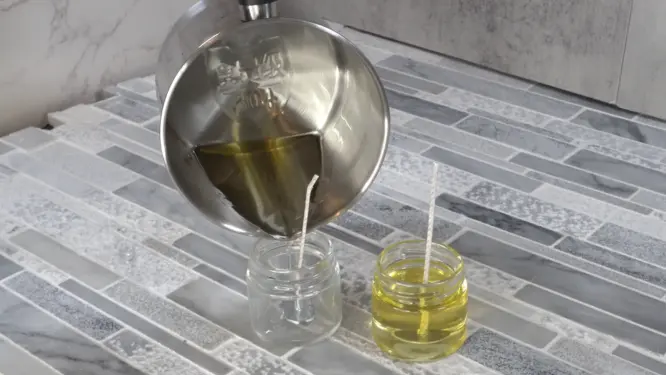 pouring DIY massage candle into jar with wick