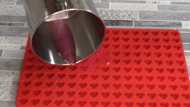 pouring candle wax into silicone heart mold for embeds