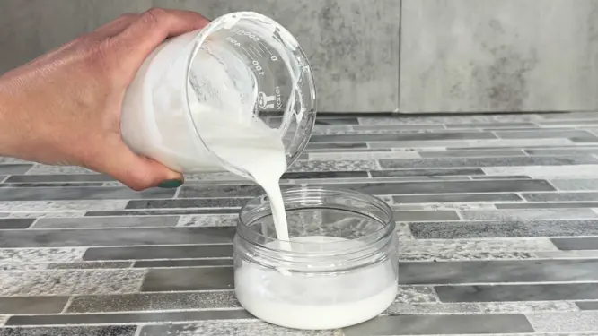 pouring emulsified body butter into plastic jar