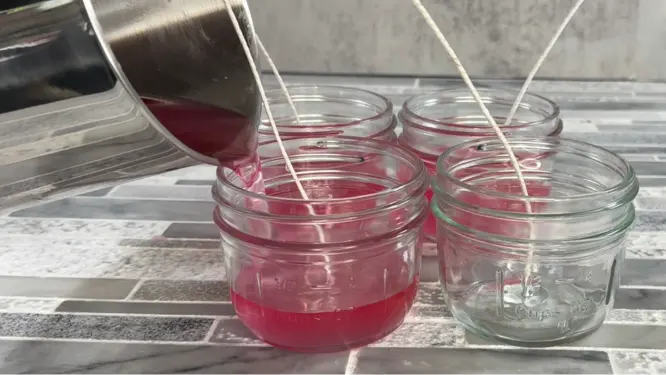 pouring pink candle wax into mason jars