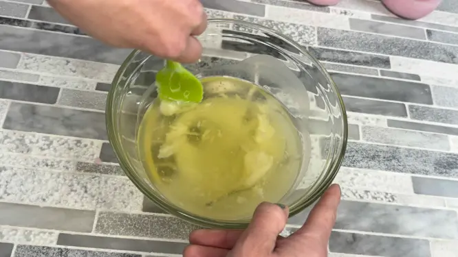 scraping edge of container of melted wax for whipped candle
