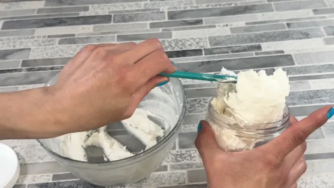 spooning whipped foot cream into glass jar
