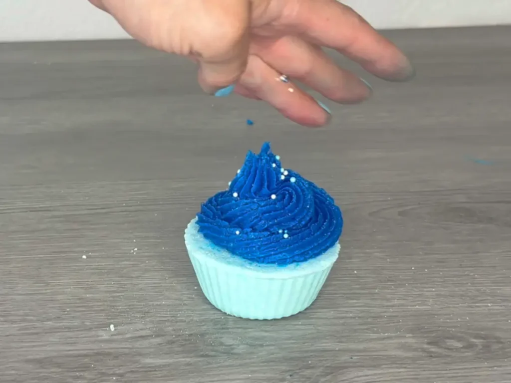 Putting sprinkles on bath bomb cupcake