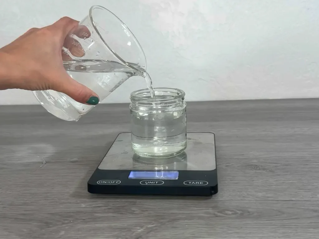 filling an empty candle jar with water to determine how much wax is needed