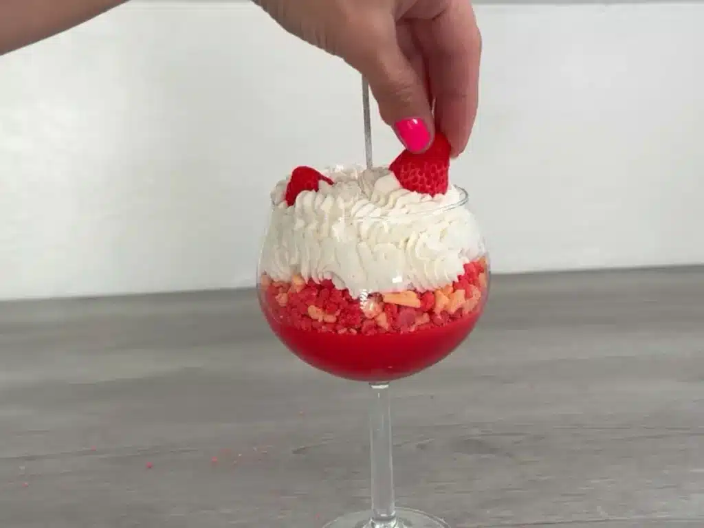 placing strawberry embed into candle whipped cream frosting
